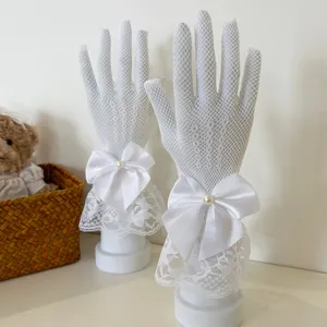 Detail view of white lace fishnet gloves with satin bow and pearl for women's wear.