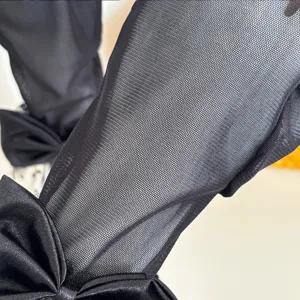 Close-up view of black mesh lace sleeve with elegant satin bow, breathable fabric detail.