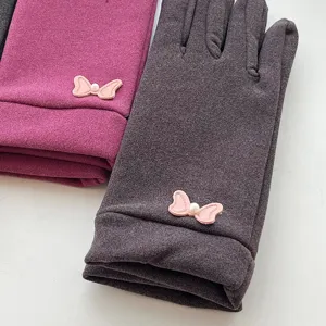 Close-up detail of winter thermal fleece-lined touch screen gloves with cute bow pearl accents.