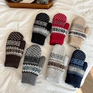 Detailed view of cozy knit mittens with Nordic snowflake pattern, thick warm winter gloves.