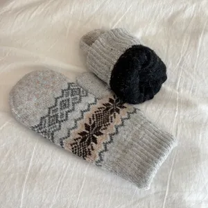 Thick fleece-lined knitted mittens with classic Nordic snowflake pattern for winter warmth.