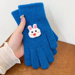 Detailed view of cozy blue knitted winter gloves featuring a cute white rabbit plush patch.