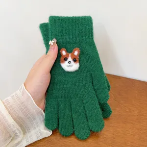 Green knit winter glove detail with cute felt corgi cartoon animal decoration close-up
