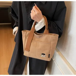 Brown canvas tote bag detail view, casual handbag with front pocket for daily use.