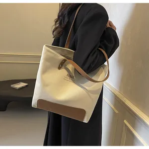 Canvas tote bag detail view, casual shoulder bag with brown leather handles and base.