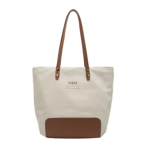 Large capacity canvas tote bag with brown leather handles and simple daily commuting style.