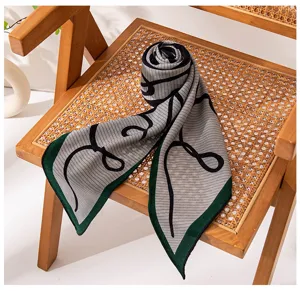 Detail shot of a stylish silk wool triangular scarf with abstract lines and green border.