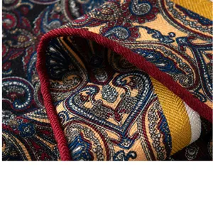 Close-up of luxury silk wool scarf with classic paisley print and red piped edge detail.