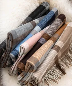 Primo piano di morbide sciarpe a quadri con motivo classico e frange su texture soffice.