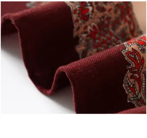 Nahaufnahme eines bordeauxroten Seiden-Wolle-Schals mit klassischem Paisley-Muster, feine Textur.