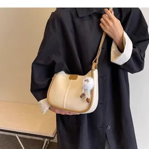 Detail view of stylish beige contrast underarm shoulder bag featuring cute fluffy charm.