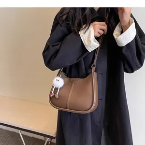 Detailed view of the stylish brown leather underarm shoulder bag with fluffy charm.