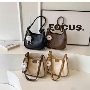 Detail view of fashionable women's underarm shoulder bags in multiple colors with plush charms.
