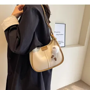 Close-up of stylish women underarm shoulder bag in cream and brown with chic plush charm.