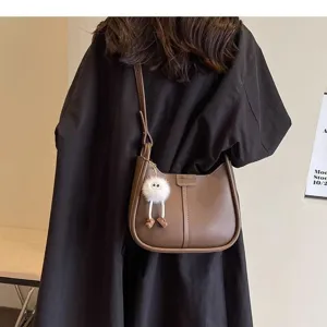 Stylish brown leather underarm shoulder bag with cute plush charm for autumn and winter.