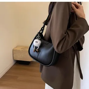 Detailed view of the stylish black underarm shoulder bag with cute fuzzy doll charm.