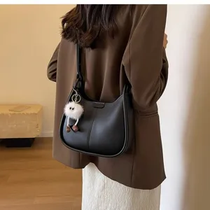 Black shoulder hobo bag detail view, stylish PU leather armpit bag with cute plush pendant.