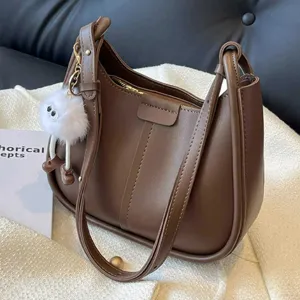 Brown underarm shoulder bag for women, stylish PU leather handbag with chic fluffy plush charm.