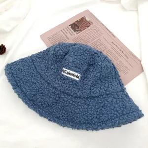 Blauer flauschiger Teddyfleece-Fischerhut mit gesticktem Etikett, kuschelige Wintermütze.