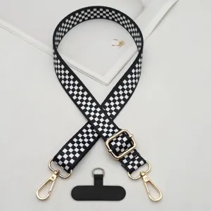 Black and white checkerboard phone strap with gold hardware and universal tether patch detail.