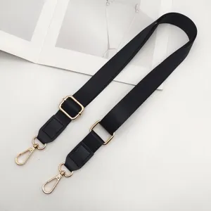 Zwart nylon tassenriem detail met duidelijk verstelbare gouden hardware en lederen uiteinden.