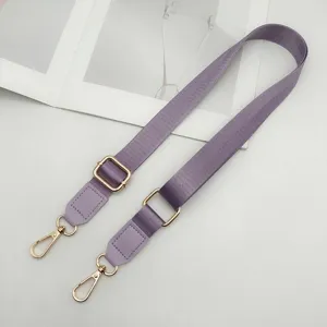 Detailopname van de paarse nylon tasriem voorzien van glanzende gouden metalen accessoires.