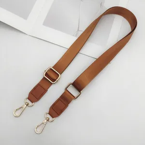 Detail van verstelbare nylon tasriem in bruin, 2.5cm breed met gouden hardware en leer.