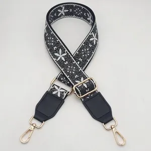 Close-up of retro ethnic embroidered wide bag strap with adjustable gold hardware.