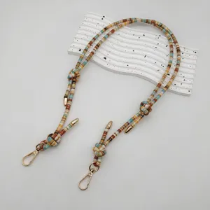Close-up detail of the colorful woven bag strap with ethnic style and gold metal clasps.