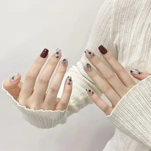 Detailed view of handmade press-on nails featuring hand-painted floral art and sparkling crystal.