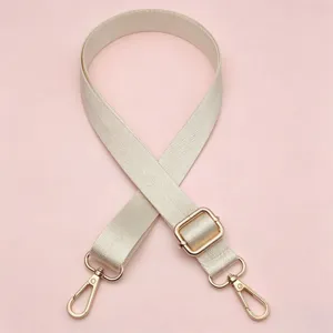 Gedetailleerde opname van de beige nylon tasriem met gouden metalen gesp accessoires.