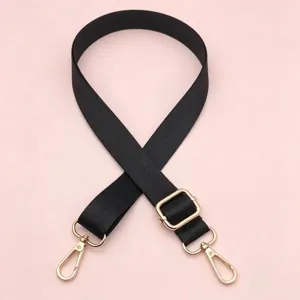 Detail van verstelbare zwarte nylon tassenband met stijlvolle gouden accessoires.