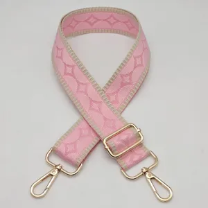 Correa de bolso tejida rosa con bordes en contraste y herrajes metálicos dorados ajustables.