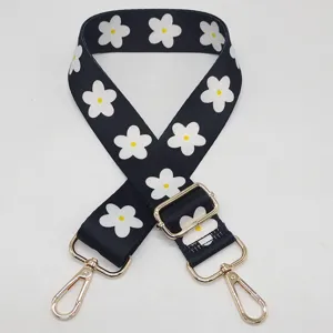 Vue détaillée de la sangle de sac large réglable à motif de marguerites noires et blanches.
