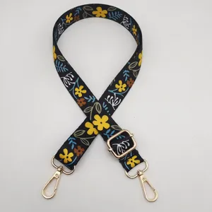 Primer plano de una correa de bolso negra de 2.5 cm con estampado floral étnico y ganchos.