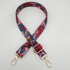 Vista detallada de la correa de bolso rosa con estampado floral y herrajes de metal dorado.