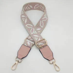 Vista dettagliata della tracolla jacquard larga con motivo floreale rosa e accessori dorati.