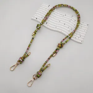 Detailed view of colorful woven bag strap with golden metal clasps and retro ethnic style.