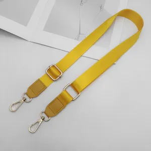 Detail van verstelbare gele nylon vervangende tasriem met lederen uiteinden en metalen haken.
