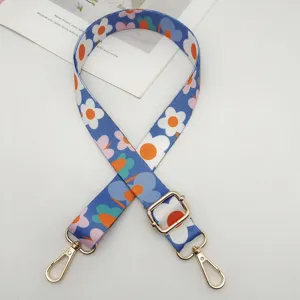 Moderna correa de bolsa ancha con estampado floral colorido y ganchos metálicos dorados.