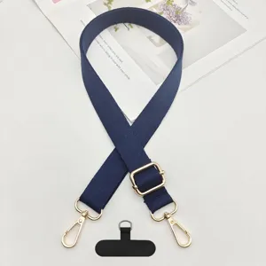 Detalle de la correa para teléfono azul oscuro con ganchos metálicos dorados y lengüeta de sujeción.