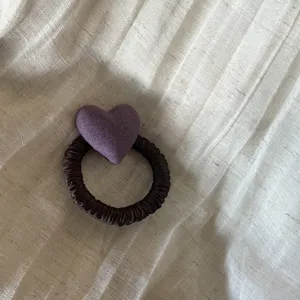 Detail shot of a cute purple fabric heart hair scrunchie, vintage ponytail hair tie accessory.