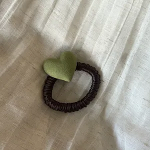 Green heart fabric hair scrunchie detail shot, cute retro ponytail holder for daily styling.