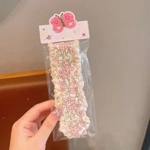 Detailansicht des blumigen Spitzen-Pony-Haar-Klettverschlusses mit schöner Schmetterlingskarte.