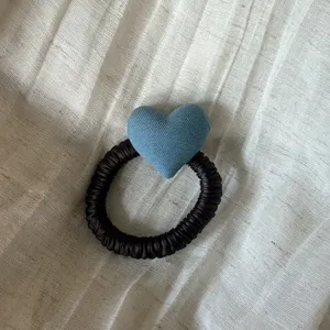 Detailed close-up of a dark brown satin hair scrunchie with a cute blue fabric heart.