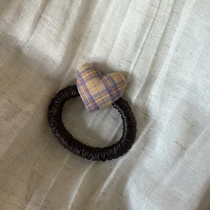 Close-up detail of the retro plaid fabric heart attached to a dark brown satin hair scrunchie.