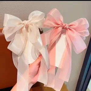 Close-up van de grote organza strik haarspeld, elegant pastel roze en beige haaraccessoire ontwerp.