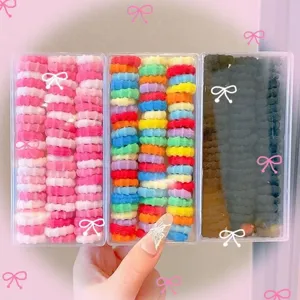 Colorful elastic hair ties for kids in clear storage boxes, cute hair accessories for girls.