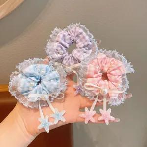 Close-up of cute plaid lace hair scrunchies with pearls and hanging star charms details.