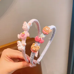 Détail de serre-tête mignon de dessin animé avec lapin rose et breloques en résine d'ours à carreaux.